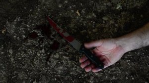 stock-footage-conceptual-footage-of-a-hand-holding-a-sharp-knife-with-blood-on-it-resting-on-a-concrete-floor
